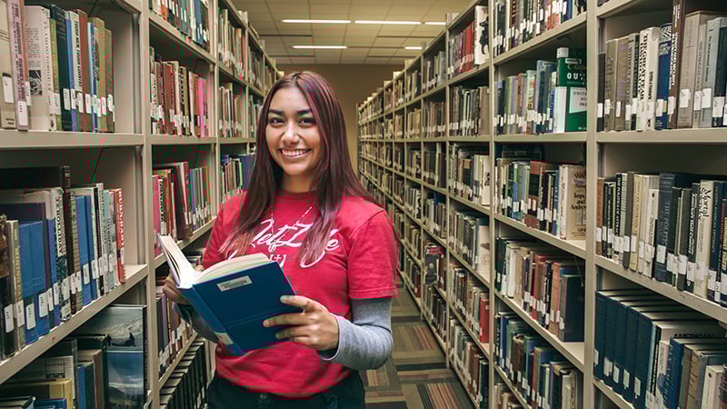 Female student reading a book in a library
